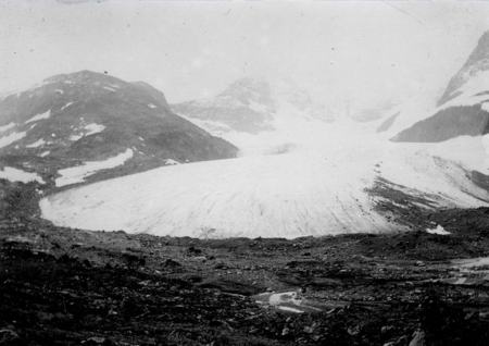 Styggedalsbreen velter seg ned mellom fjellene i et historisk foto i sort hvitt.